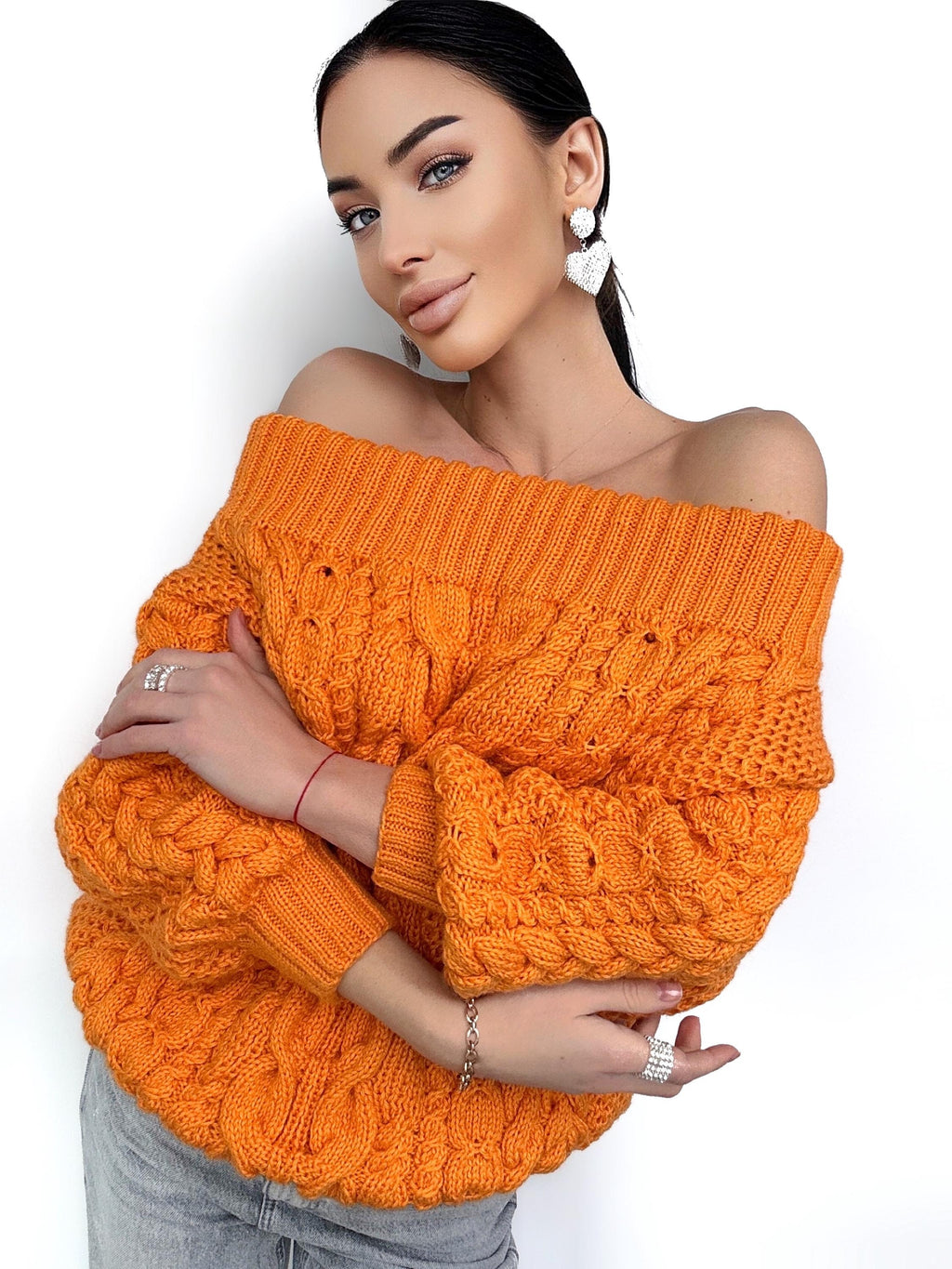 May include: A bright orange off-the-shoulder sweater with a chunky cable knit pattern.