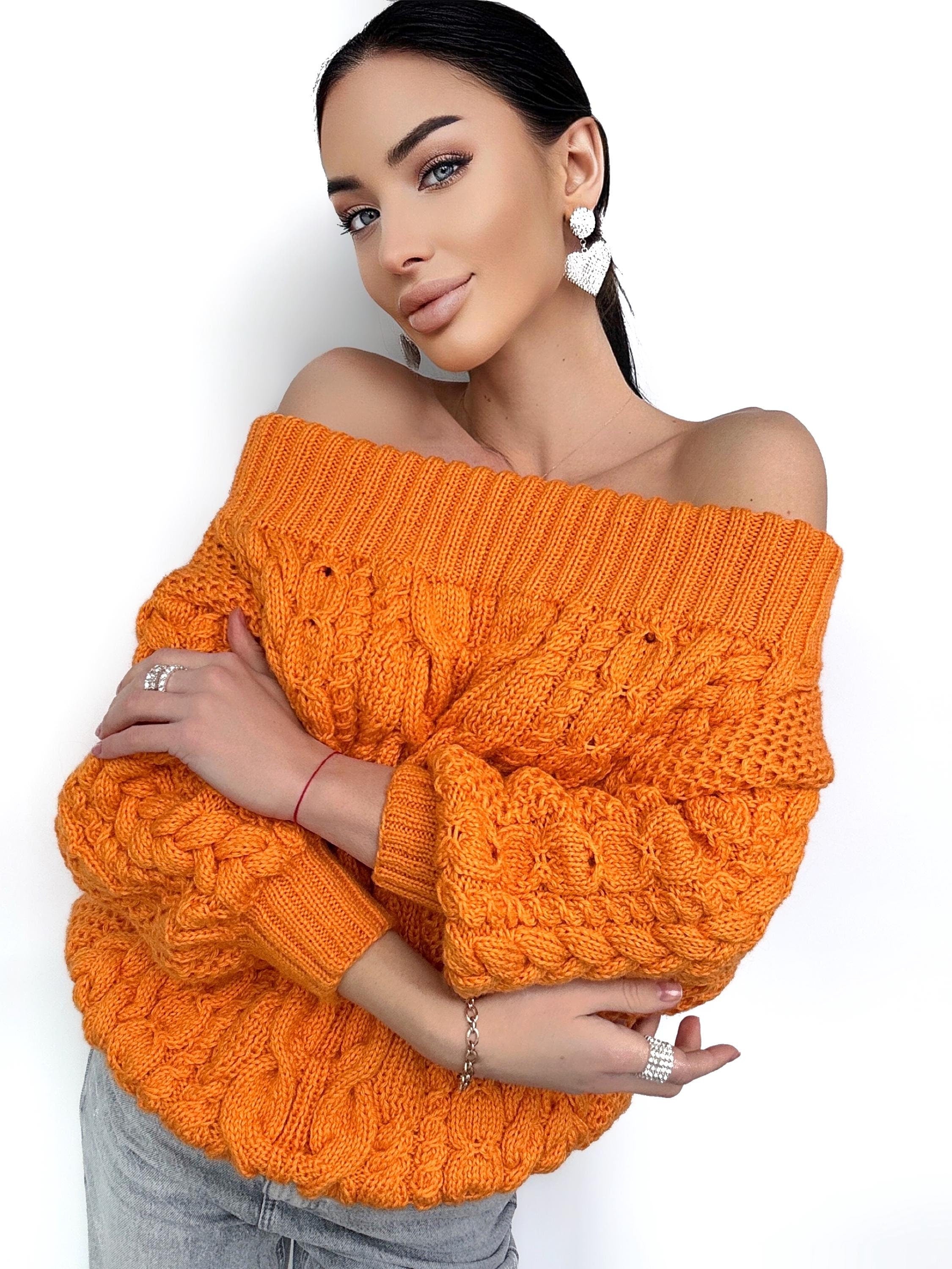 May include: A bright orange off-the-shoulder sweater with a chunky cable knit pattern.
