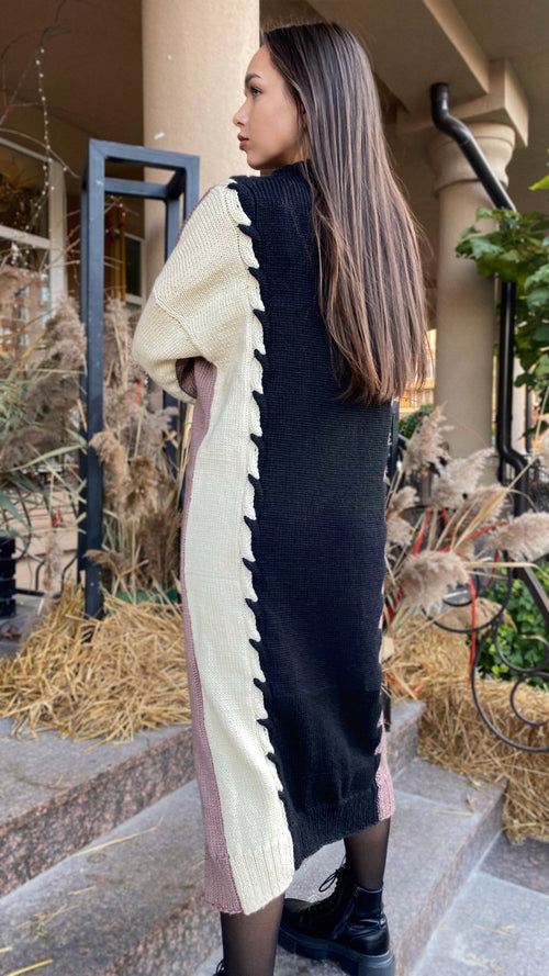 May include: A long-sleeved knitted dress with a black and cream color block design. The dress has a unique braided detail down the side.