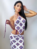 May include: A white crochet halter top and matching skirt set with a geometric pattern in purple and blue. The top ties at the neck and waist. The skirt is a midi length.