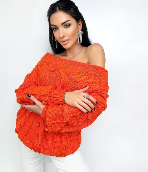 May include: Orange off-the-shoulder sweater with a cable knit pattern and pom-poms.